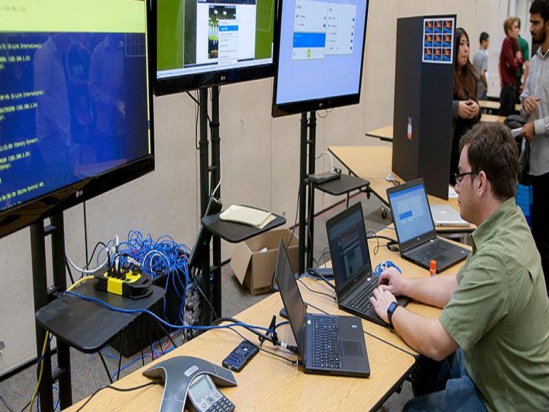 individual in front of multiple monitors at a Cyber Fair